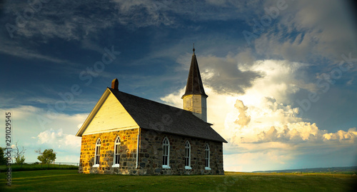 Old stone Prairie Church with storm clouds behind it 