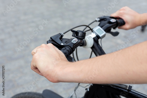 Young active man on a bike resting his hands on the handle bars, concrete background. Speedometer and led lighting equipment accessories shown. Outdoor cycling activity, urban biking trip concept