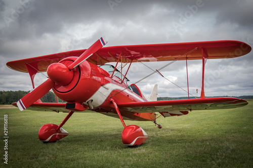 Beautiful red vintage airplane standing on the green grass near the airport field. Pitts Special Biplane