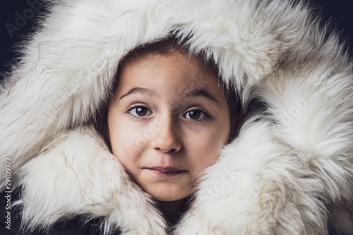 Close up portrait of a young girl dressed with an eskimo jacket looking at the camera