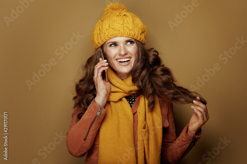 happy young woman talking on cell phone and on beige background