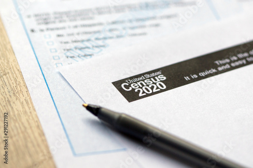 Closeup of United States Census 2020 form informational copy and a ballpoint pen on wooden background.