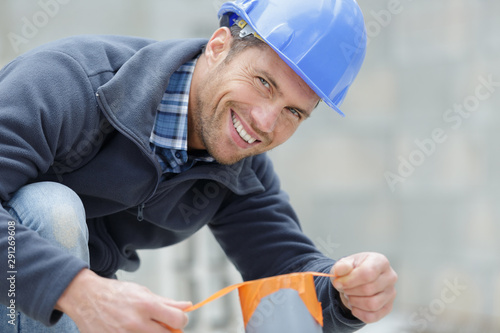 happy male worker with tape measure at hand