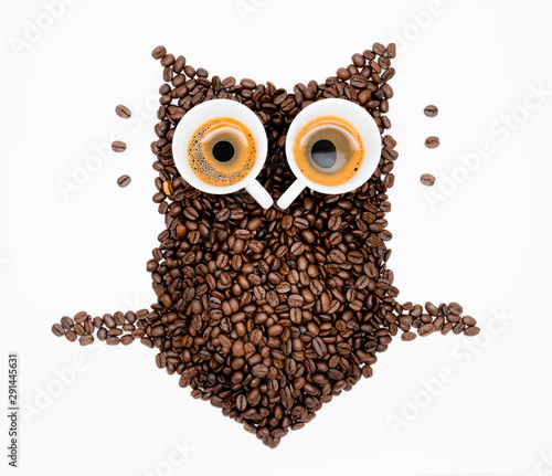 Owl made of roasted coffee beans and two cups. A symbol for night people.