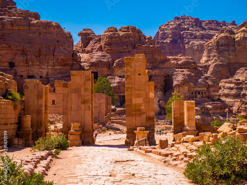 Cobblestone street leading through large sandstone columns of a historic monument, ruin in the desert of the historic site of Petra, Jordan