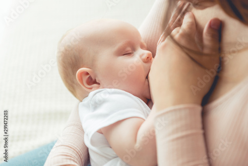 cropped view of mother breastfeeding her child in apartment