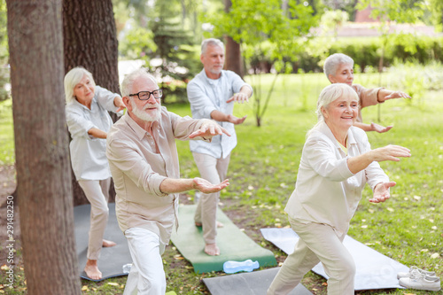 Smiling senior people doing qigong exercise outdoors