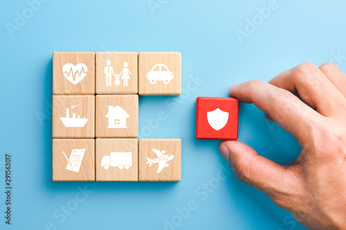 Hand holding red wooden blocks with insurance icons. family, life, car, travel, health and house insurance icons, blue background, Insurance concept