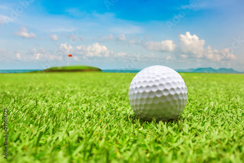 Golf ball on green grass with the ocean background