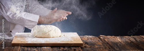 Chef or baker dusting dough with flour