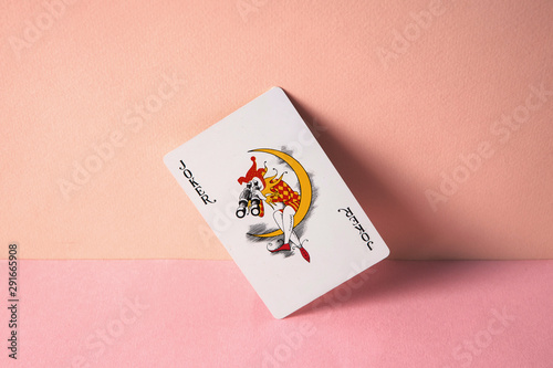 Joker playing card on pink background.