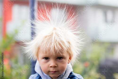 Cute little boy with static electricy hair, having his funny portrait taken outdoors