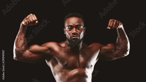 Confident bodybuilder demonstrating strong biceps and shoulders