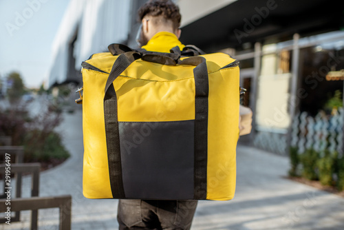 Delivery Man standing with yellow thermo backpack for food delivery with empty space to copy paste on the street outdoors