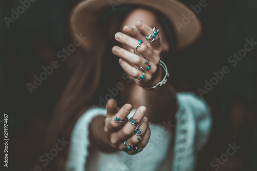 Boho chic woman in a straw hat in a white short blouse and with silver turquoise jewelry. Boho fashion. Hippie style, stylish girl with silver rings