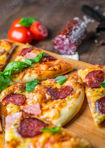 Pepperoni Pizza with Mozzarella cheese, salami, ham, Spices and Fresh basil. Italian pizza on wooden table background