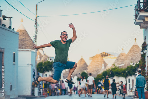 happy tourist take selfie photo jumping in Alberobello town, Apulia, southern Italy. The town of alberobello is famous for the typical trulli houses. vintage color style