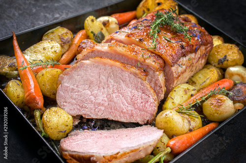 Traditional roasted dry aged veal tenderloin with carrots and potatoes offered as closeup on a metal tray