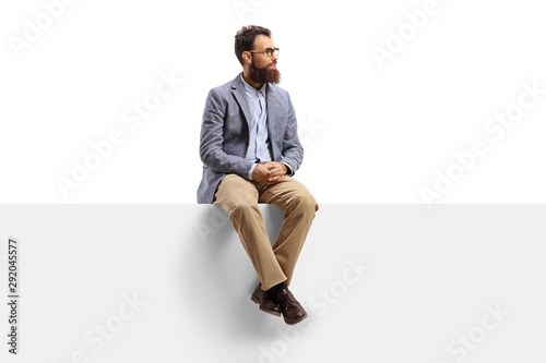 Bearded man sitting on a white banner and looking to the side