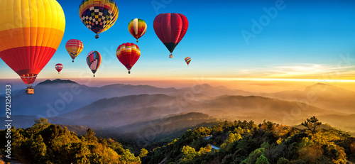 Hot air balloons flying over sea of mist awakening in a beautiful hills at sunrise in Chiang Mai, Thailand.