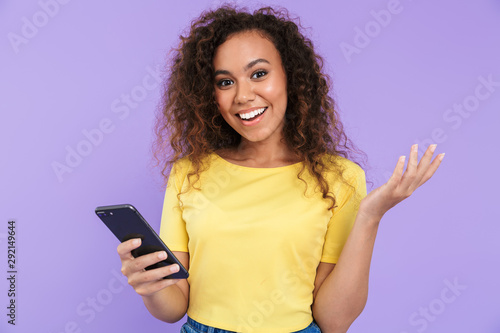 Image of charming african american woman smiling and holding smartphone