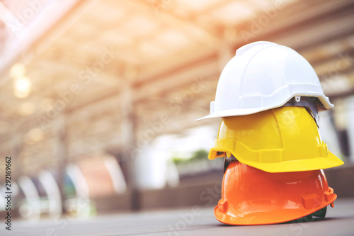 orange yellow and white hard safety wear helmet hat in the project at construction site building on concrete floor on city with sunlight. helmet for workman as engineer or worker. concept safety first