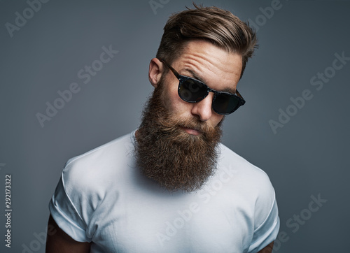 Stylish young hipster with a long beard wearing sunglasses