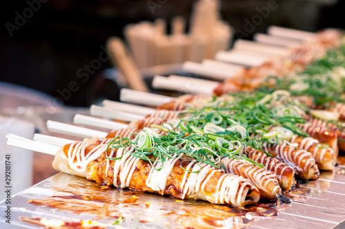 Okonomiyaki on wooden sticks with soy sauce and mayonaise topped with green onion at Nishiki market, Kyoto