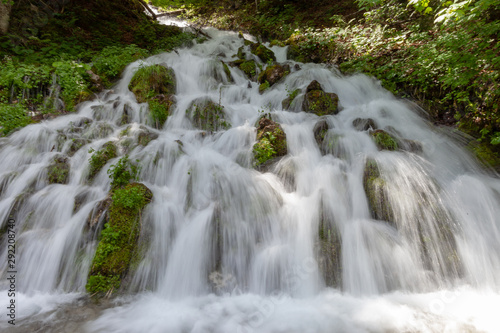 Waterfall rushing down a steep hill in a forest.