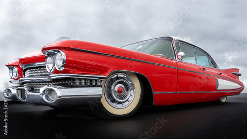 Side view of a classic american car from the fifties. Low angle view showing red paint and chrome fender and grill.