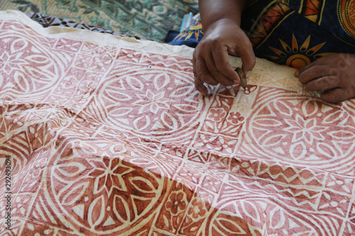 A Samoan lady drawing traditional pattern with mud water on a handmade mulberry paper.