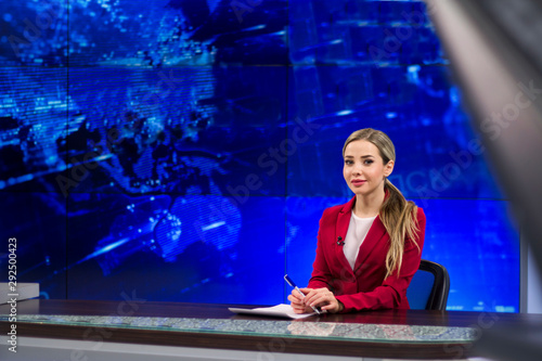 News anchor in the TV Studio . Beautiful girl reading the news, on a blue screen background