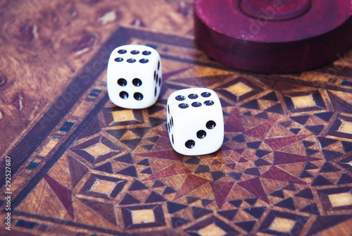 Backgammon. Board game. White cubes and chips on a blackboard.