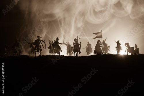 Medieval battle scene with cavalry and infantry. Silhouettes of figures as separate objects, fight between warriors on dark toned foggy background. Night scene.