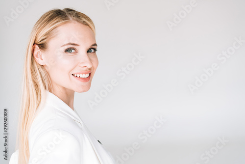 smiling beautiful young blonde woman isolated on grey