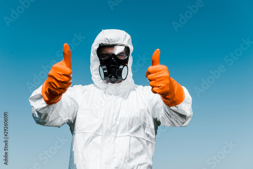 exterminator in protective mask and uniform standing and showing thumbs up