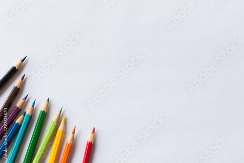 colorful colored pencil and white paper on wooden background