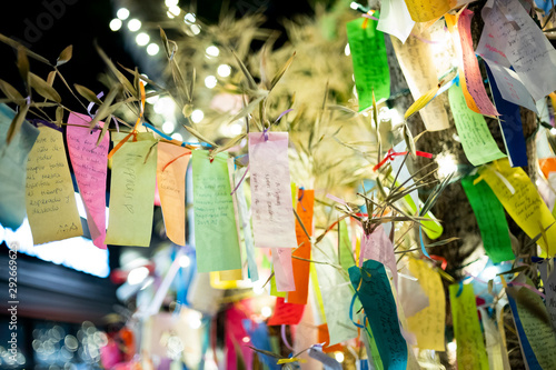 Wishes written on Tanzaku, small pieces of paper, and hung on a Japanese wishing tree, located in the Little Tokyo section of Los Angeles, California, photographed at an outdoor mall at night. 