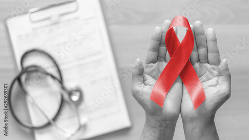 World aids day and national HIV/AIDS and ageing awareness month with red ribbon on woman hand support (bow isolated with clipping path)