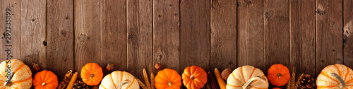 Autumn bottom border banner of pumpkins and fall decor on a rustic wood background with copy space