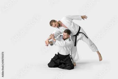 Two caucasian men are practicing aikido on the tatami (isolation path included)