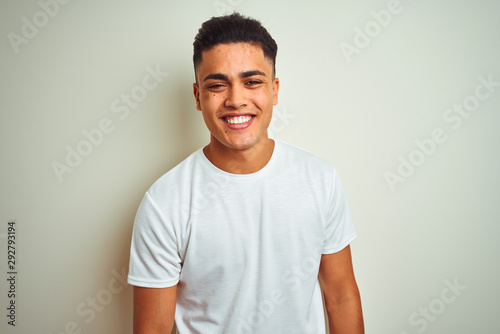 Young brazilian man wearing t-shirt standing over isolated white background with a happy and cool smile on face. Lucky person.