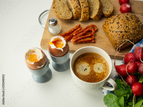 Pyszne, zdrowe śniadanie. Jajka na miękko z pieczywem, dodatkami i kawą leżące na białym tle. Widok z góry.