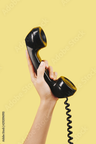 Hand of person holding black telephone receiver