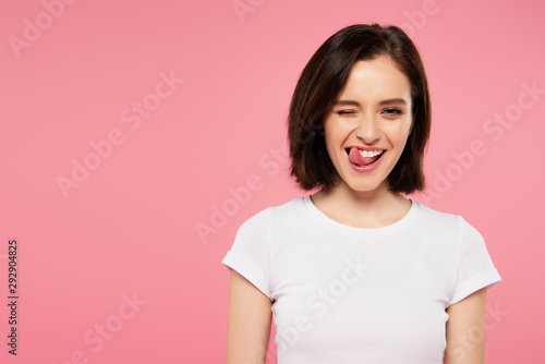 beautiful girl showing tongue and winking isolated on pink