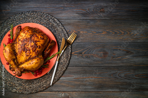 Baked chicken for festive dinner. Cooked whole chicken or turkey with herb rosemary and berries on wooden table. Christmas, Thanksgiving, holidays concept. Copy space