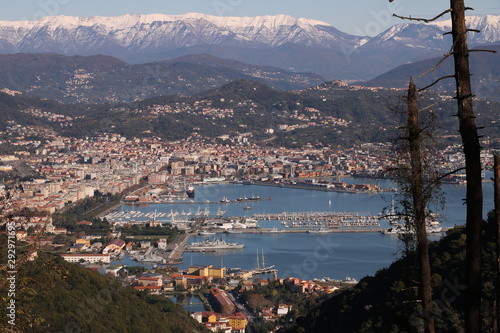 Panoramic view of La Spezia in Liguria shot from above. A cruise ship in the port, numerous moored sailboats and commercial port cranes..