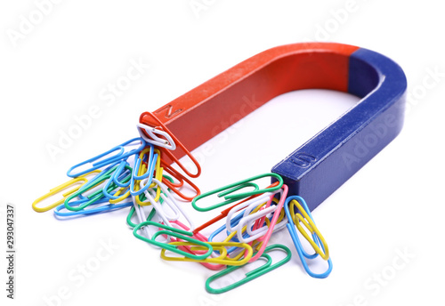 Horseshoe magnet attracting paper clips on white background