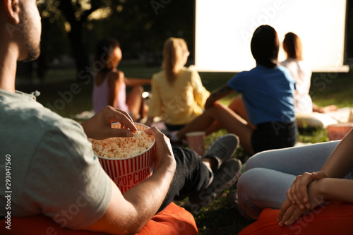 Young people with popcorn watching movie in open air cinema, closeup. Space for text