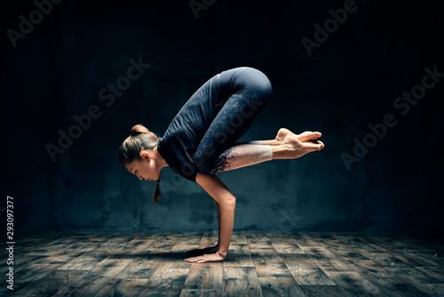 Young woman practicing yoga doing forearm stand crane pose asana in dark room